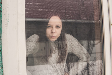 Sad beautiful woman looking through the window