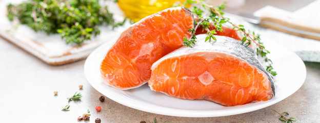 Fresh raw salmon fish steaks on white kitchen background. Banner