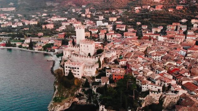 Lake Lago Garda - view of Malcesine village. Old castle on rock Italy. Aerial video sunset.