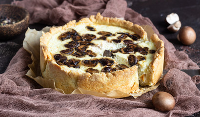Quiche with champignons and cheese on dark brown concrete background. Savory tart with mushrooms. Cope space.