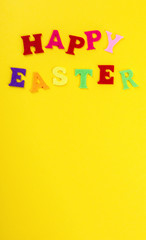 Easter concept. Inscription in colored letters Happy Easter on a yellow background.Top View. Flat Lay