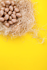 Easter background with golden paint easter eggs in the nest  on yellow paper. Happy Festive concept.Top View. Flat Lay.Copy space for Text