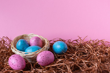 Fototapeta na wymiar Six pink and blue Easter eggs in a basket on pink background. Easter celebratory wallpaper with copy space.