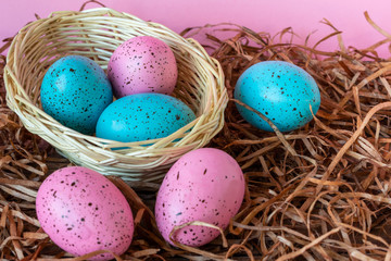 Fototapeta na wymiar Six pink and blue Easter eggs in a basket on pink background. Close-up Easter celebratory wallpaper.