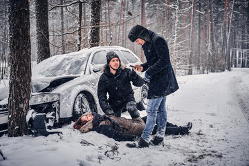 Witness of the accident helps the injured couple to contact the rescue service. The car got into a skid and crashed into a tree on a snowy road. 