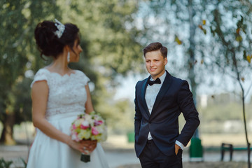 Wedding couple embracing a green park in daylight.