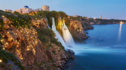 Night view of water cascading from platform into Mediterranean sea in Antalya. Illuninated Lower Duden Waterfall in popular seaside resort city Antalya