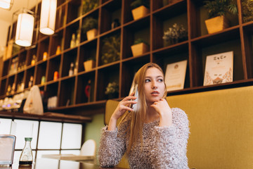 Young woman with smartphone do shopping, connecting with internet, listening to music, learning. Student girl in cafe. Education, technology concept