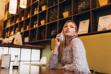 Young woman with smartphone do shopping, connecting with internet, listening to music, learning. Student girl in cafe. Education, technology concept