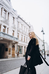 Young blondie business woman rushing to a business meeting. Walking along old historic european town 