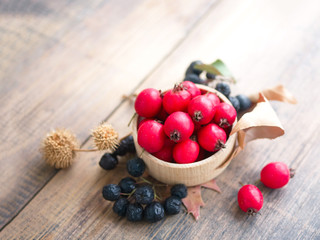 Hawthorn tincture in a cup and black mountain ash on a wooden table. Herbal medicine. Selective focus.