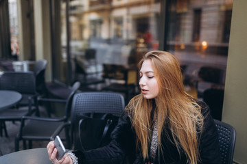 Blondie young girl in street outdoor cafe with smartphone chating and communicate