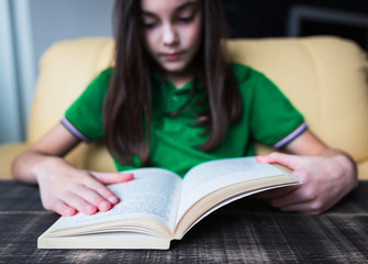 background. beautiful girl reading a book while sitting in a chair in her room