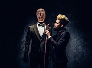 An elegantly dressed fashion designer with expressive style working with custom made men's suit in...