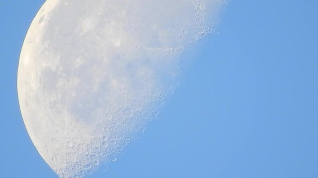 A 20 sec close-up shot of the moon moving across the daytime sky.