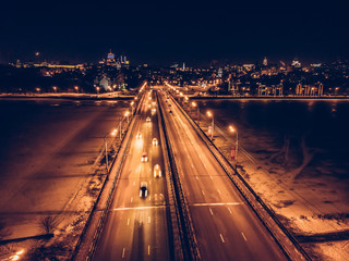 Fototapeta na wymiar Illuminated bridge with blurred car traffic on night city background, aerial view, drone photo