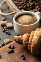 Black fried coffee beans in cafe with cookie and cake on dark textured background