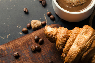 Black fried coffee beans in cafe with cookie and cake on dark textured background
