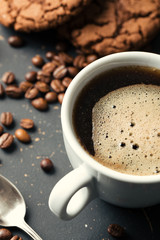 Black fried coffee beans in cafe with cookie and cake on dark textured background