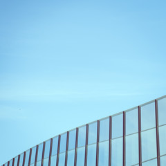 The upper part of the building has glass windows of a modern building, square format. Toned.