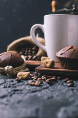 Black fried coffee beans in cafe with cookie and cake on dark textured background