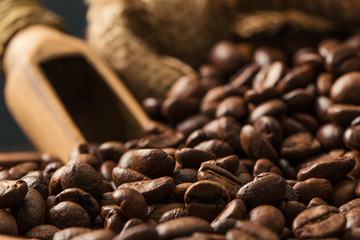 Black fried coffee beans on dark textured background