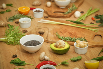  Wooden cutting board surrounded with a variety of herbs, spices, fruits and vegetables