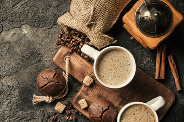 Black fried coffee beans in cafe with cookie and cake on dark textured background