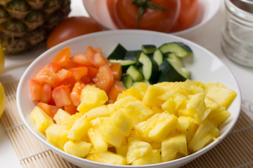 Fruit salad with pineapple, cucumber and tomato in bowl