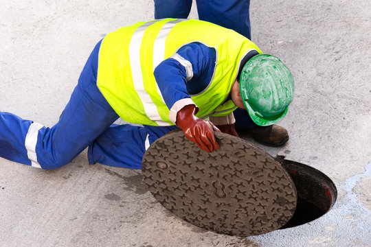 Sewerage Utility  Workers Moves The Manhole Cover To Cleaning The Sewer Line