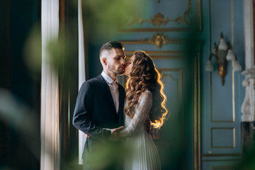 Sensual portrait of bride and groom in beautiful warm backlight in classic hall
