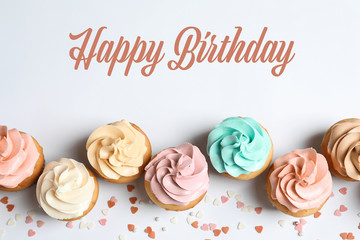 Flat lay composition with delicious birthday cupcakes and space for text on white background