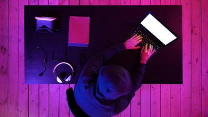 Cybercrime, hacking and technology concept - male hacker in dark room writing code or using...