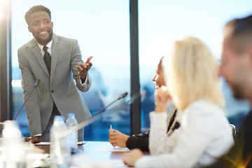 Happy young African-american speaker explaining to audience his methods and strategies of leading...