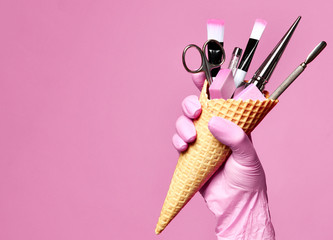 Manicure and pedicure abstract concept. Hand hold  waffles cone with instruments for nails salon and spa brush nail file  - 249216455