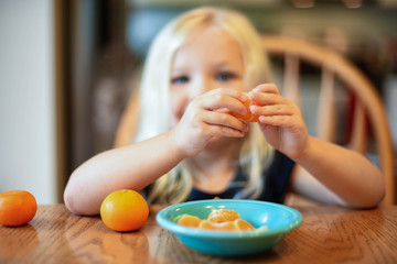 Little girl having a healthy snack of fresh clementines