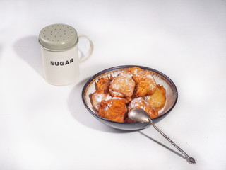 Homemade crumbs, sprinkled with powdered sugar and a jar of powdered sugar on a white table.