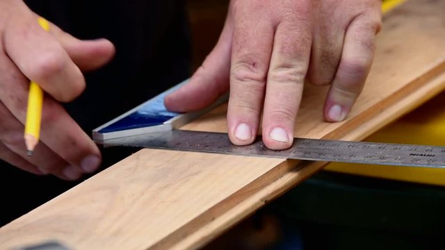 Man using set square to measure and mark timber