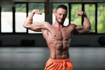 Naklejka na ściany i meble Biceps Pose Of A Young Man In Gym