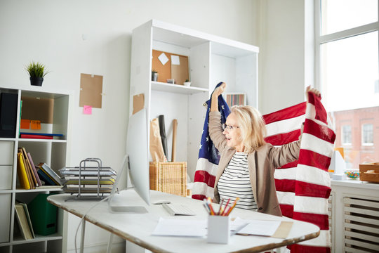 Portrait Of Proud American Woman Holding Flag While Watching Sports Match At Workplace In Office, Copy Space