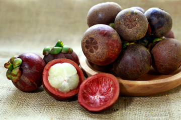 purple mangosteen on wooden bowl with burlap background