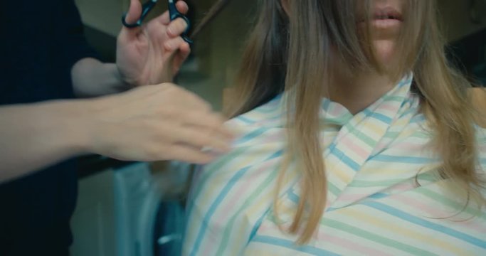 Young woman cutting her firend's hair at home