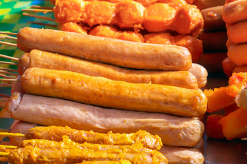 Sausages on wooden skewers, baked on the grill, lie on the table with a traditional Asian street food. Close-up