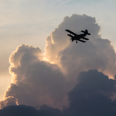 Silhouette of a biplane airplane on a moody heavy cloudy sunset