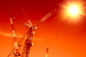 building crane lift with sun hot heat sky in construction site at orange sunset tone.