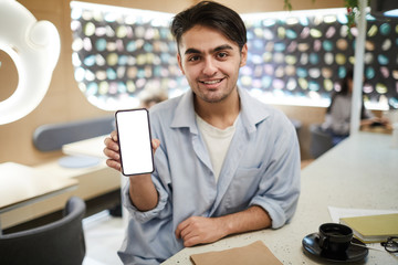 Happy guy showing smartphone with important data on screen while sitting by table in college cafe