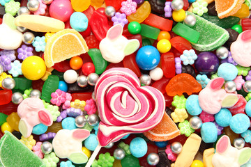 Fototapeta na wymiar Assorted variety of sweet sugar candies includes lollipops, Easter bunny jelly, gummy bears, gum balls and sugar fruit slices.