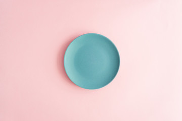 Clean empty blue plate on pink background, top view