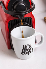 Red espresso coffee machine pouring coffee on a white decorated mug