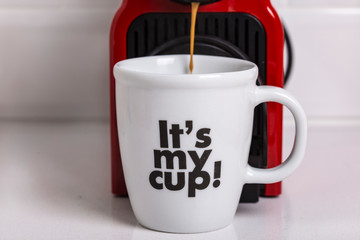 Red espresso coffee machine pouring coffee on a white decorated mug